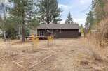 This charming brown home features a spacious wooden deck, perfect for outdoor entertaining and enjoying the surrounding natural beauty.