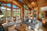 Experience breathtaking mountain views from this stunning living room, featuring a soaring vaulted ceiling with exposed wooden beams and expansive windows that flood the space with natural light.