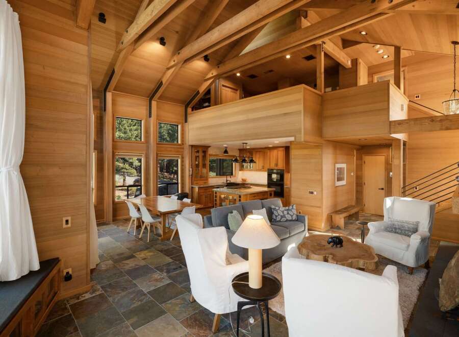Experience luxurious living in this stunning modern home featuring a soaring vaulted ceiling with exposed wooden beams and extensive natural wood paneling throughout.