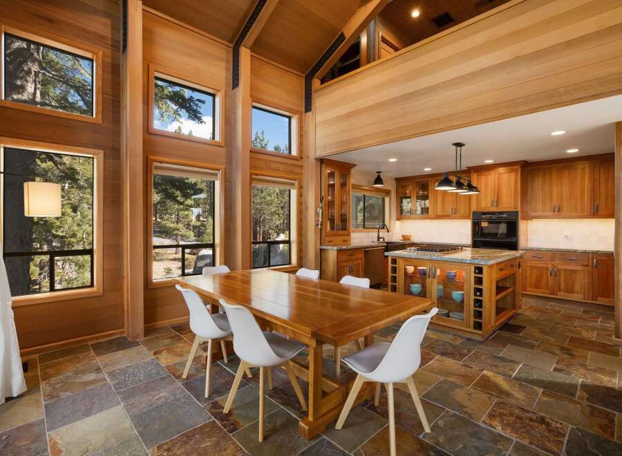 Experience luxurious mountain living in this stunning home featuring a spacious dining area with a large wooden table and white chairs, perfect for gatherings.