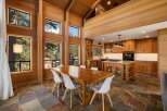 Experience luxurious mountain living in this stunning home featuring a spacious dining area with a large wooden table and white chairs, perfect for gatherings.