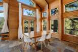 Experience breathtaking natural beauty from this stunning dining room, featuring floor-to-ceiling wood paneling and expansive windows that frame lush forest views.