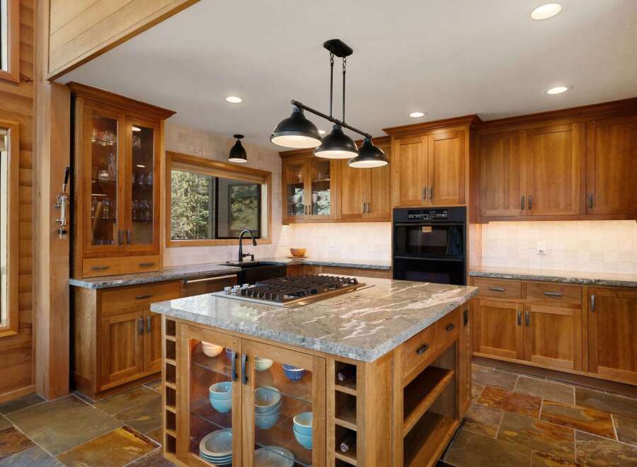 Experience luxury in this stunning kitchen, featuring custom wood cabinetry and a large granite-topped island with a built-in gas range.