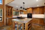 Experience luxury in this stunning kitchen, featuring custom wood cabinetry and a large granite-topped island with a built-in gas range.