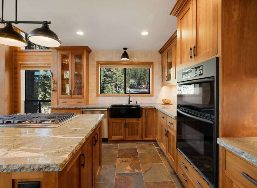 Experience luxury in this stunning kitchen featuring warm wood cabinetry and a spacious granite island with a built-in gas range.