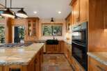 Experience luxury in this stunning kitchen featuring warm wood cabinetry and a spacious granite island with a built-in gas range.