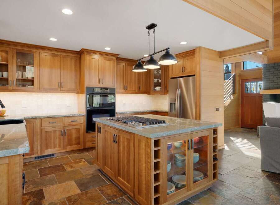 This spacious kitchen boasts custom wood cabinetry and a large island with a built-in gas range, perfect for culinary enthusiasts.