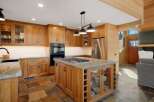 This spacious kitchen boasts custom wood cabinetry and a large island with a built-in gas range, perfect for culinary enthusiasts.