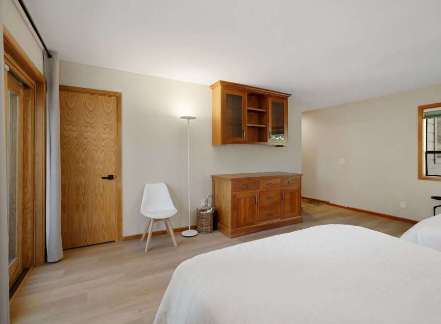 This spacious bedroom features a warm and inviting ambiance with its light wood flooring and neutral-toned walls.
