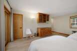 This spacious bedroom features a warm and inviting ambiance with its light wood flooring and neutral-toned walls.