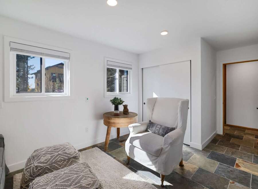Step into this inviting living space featuring a comfortable white armchair adorned with a decorative pillow, perfect for relaxation.