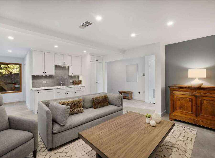 This inviting living space features a comfortable gray sofa adorned with leopard print pillows, complemented by a rustic wooden coffee table.