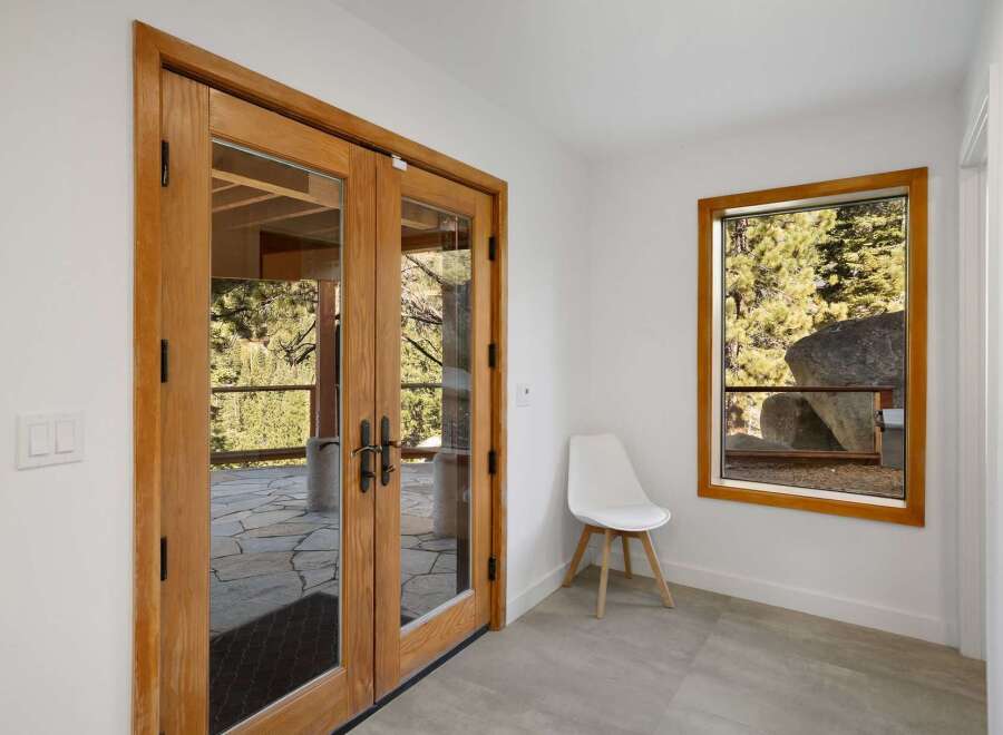 Step outside through elegant double wooden doors to a stone patio, offering a serene connection with the surrounding nature.