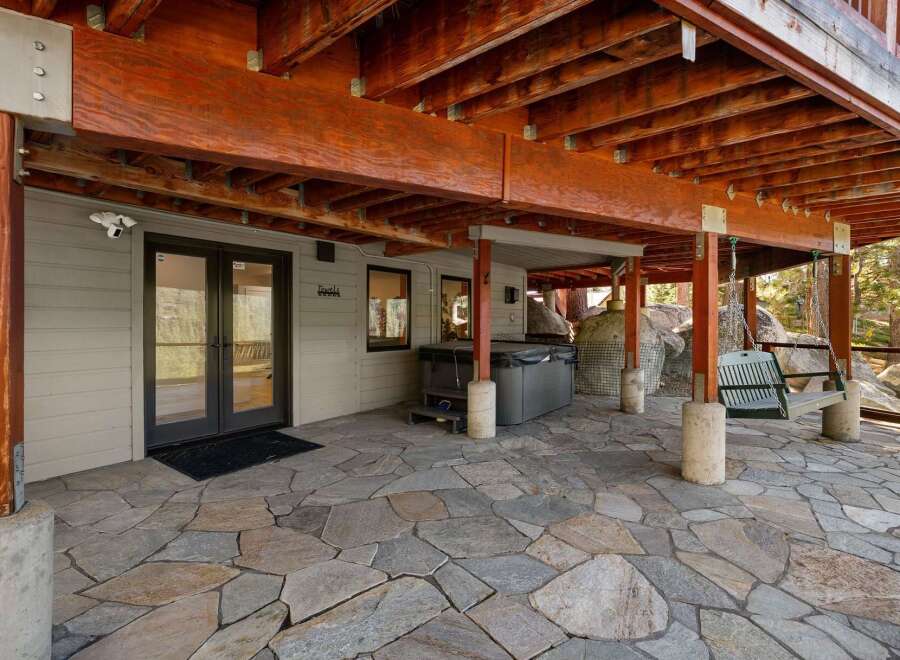 Enjoy outdoor living with this spacious patio featuring a relaxing hot tub and a charming swing bench.