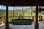 Enjoy breathtaking mountain views from this charming porch swing, perfect for relaxing and taking in the serene forest landscape.