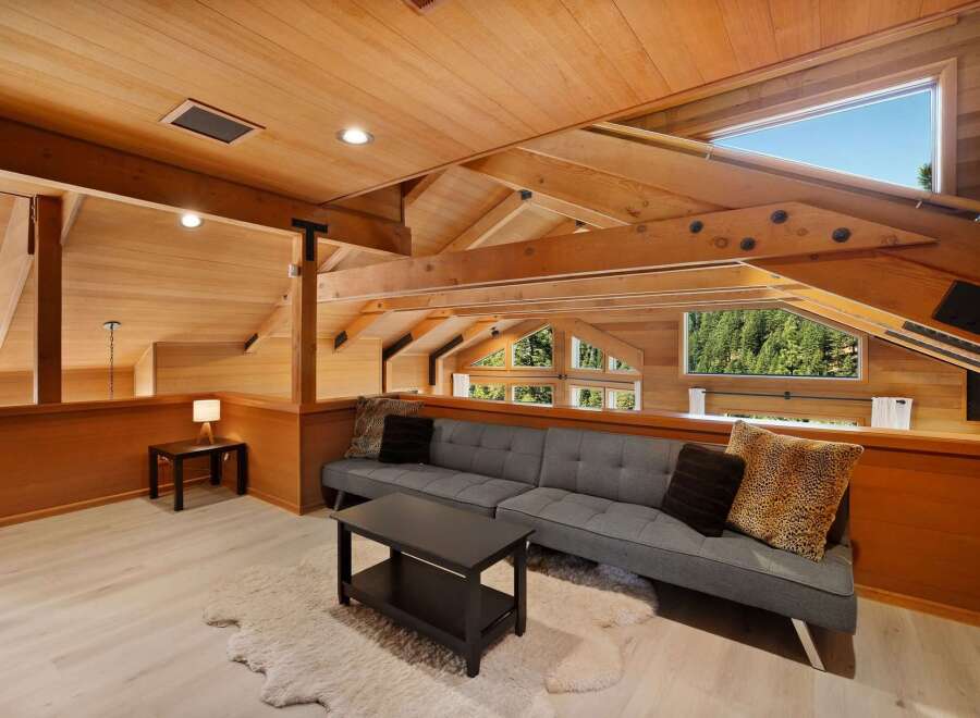 Experience breathtaking views from this stunning loft living space, featuring a modern gray sofa and a cozy sheepskin rug.