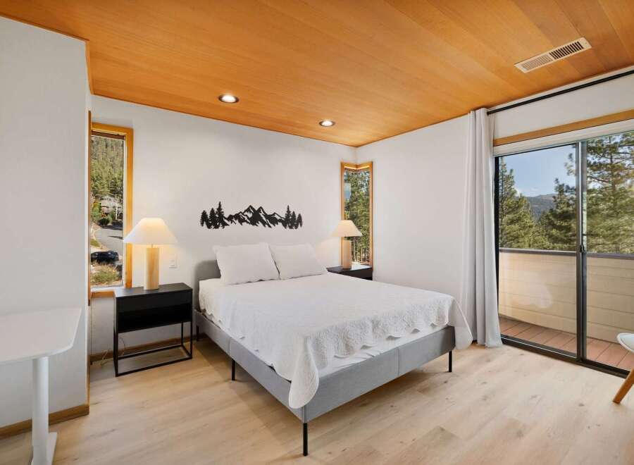 Experience serene mountain living in this charming bedroom, featuring a cozy queen-size bed adorned with a white quilted coverlet.
