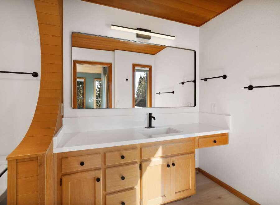 This beautifully appointed bathroom features a spacious vanity with ample storage, complemented by a sleek, modern faucet and a large, frameless mirror.