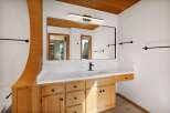 This beautifully appointed bathroom features a spacious vanity with ample storage, complemented by a sleek, modern faucet and a large, frameless mirror.
