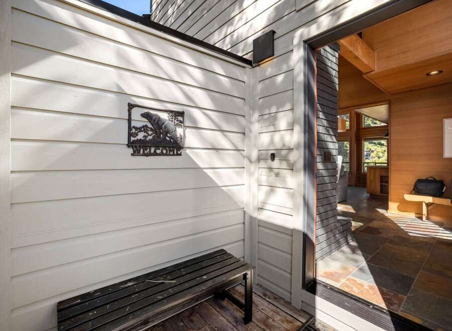 Welcome guests with this charming entryway featuring a rustic bear-themed welcome sign and a sturdy wooden bench.