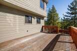 Enjoy the outdoors from this expansive wooden deck, perfect for entertaining or relaxing amidst the scenic beauty of mature pine trees.