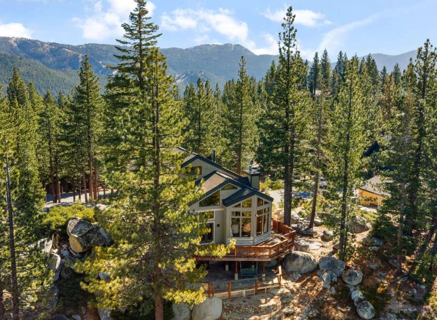 Nestled amidst towering pine trees and large granite boulders, this stunning mountain home offers breathtaking views of the surrounding landscape.