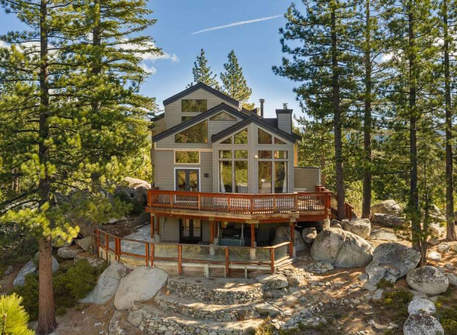 Nestled amidst towering pine trees and surrounded by natural boulders, this stunning multi-level home offers a serene mountain retreat.