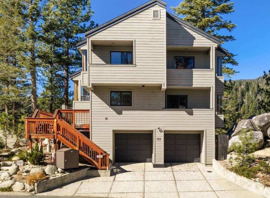 This stunning multi-story home offers a modern aesthetic with its light-colored siding and dark-trimmed windows.