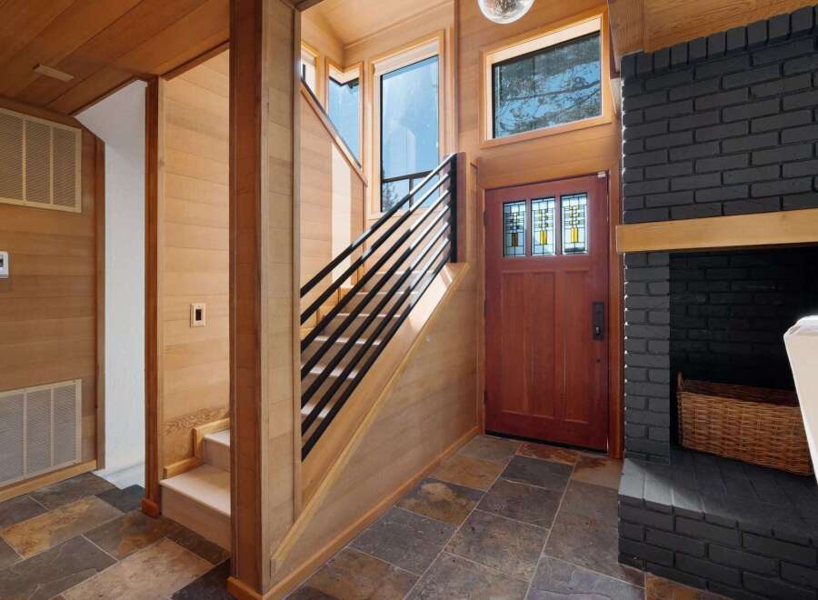 Step into a warm and inviting entryway featuring rich wood paneling and a striking black brick fireplace.