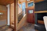 Step into a warm and inviting entryway featuring rich wood paneling and a striking black brick fireplace.