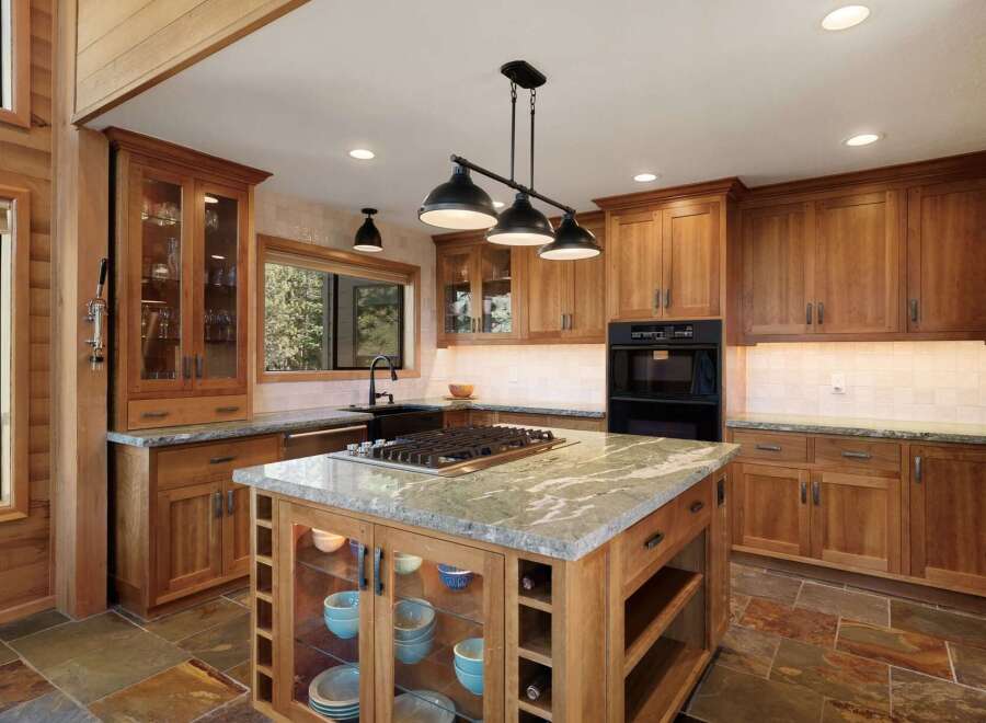 Experience luxury in this stunning kitchen, featuring custom wood cabinetry and a large granite-topped island with a built-in gas range.