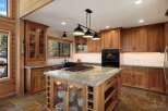 Experience luxury in this stunning kitchen, featuring custom wood cabinetry and a large granite-topped island with a built-in gas range.