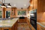 Experience luxury in this stunning kitchen featuring warm wood cabinetry and a spacious granite island with a built-in gas range.