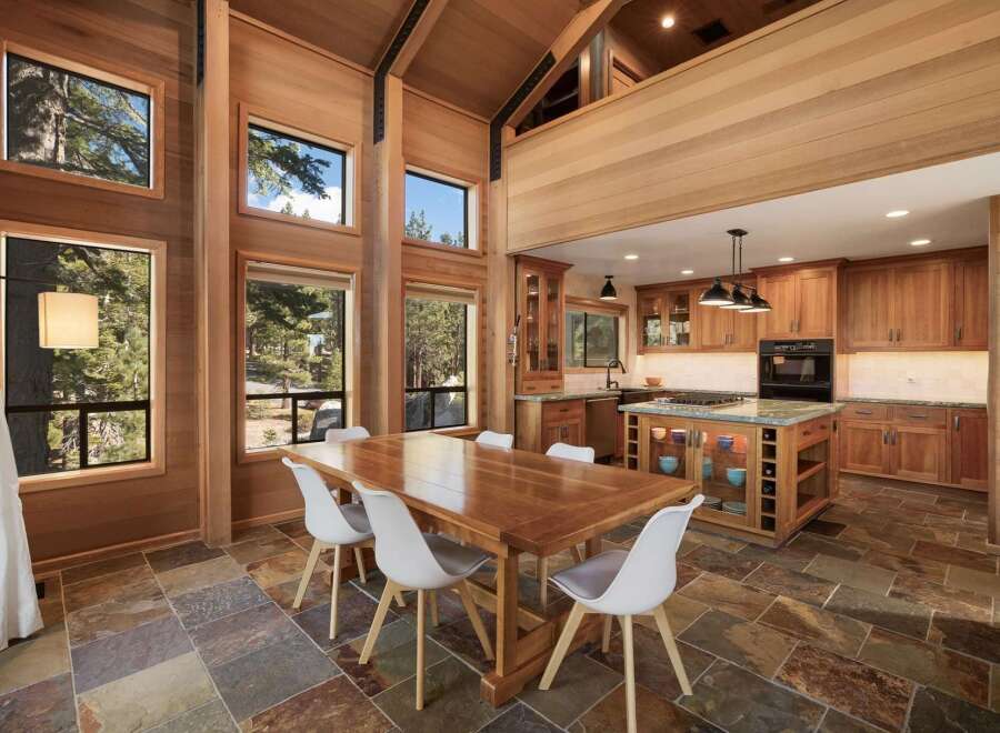 Experience luxurious mountain living in this stunning home featuring a spacious dining area with a large wooden table and white chairs, perfect for gatherings.