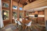 Experience luxurious mountain living in this stunning home featuring a spacious dining area with a large wooden table and white chairs, perfect for gatherings.