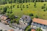 Discover this charming property nestled against a lush green hillside, offering a serene retreat.