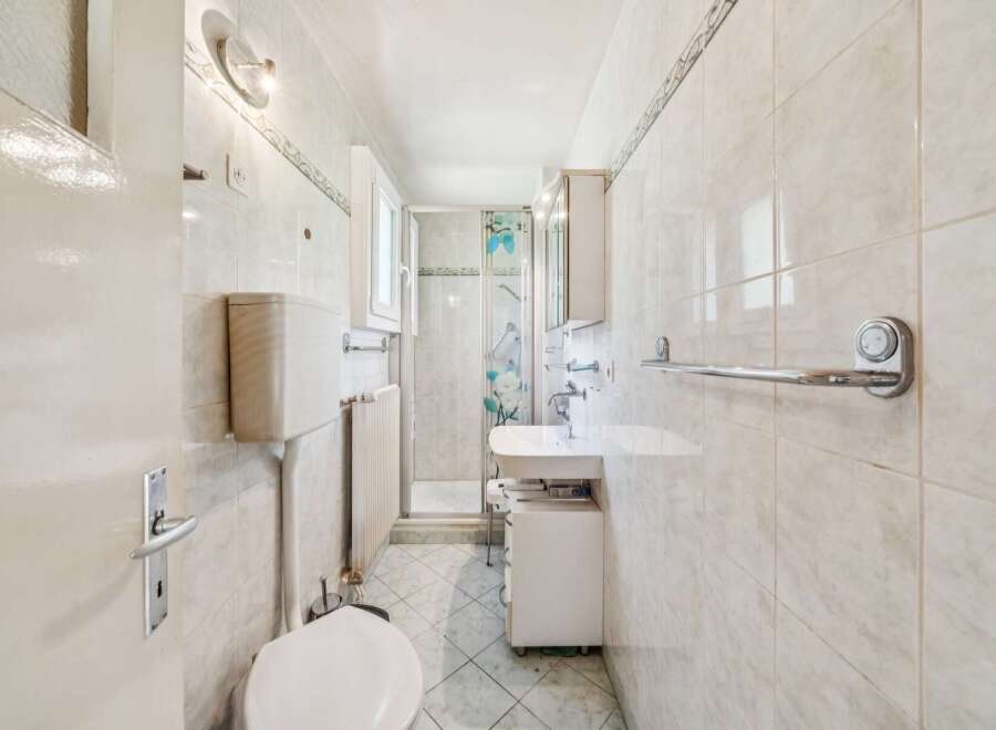 This bright and airy bathroom features a modern shower enclosure with a decorative floral curtain.