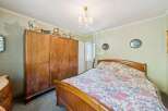 Step into a charming bedroom featuring a large, vintage wooden wardrobe and a cozy bed adorned with a floral comforter.