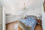 This charming attic bedroom features a comfortable bed adorned with a blue patterned comforter, perfect for a cozy retreat.