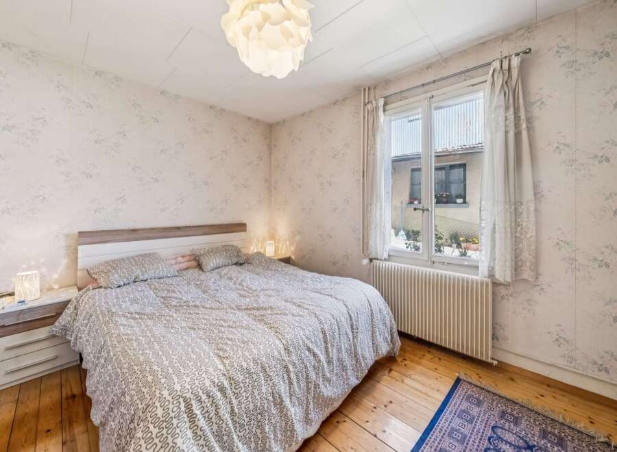 This charming bedroom features a comfortable bed with a patterned duvet and matching pillows, complemented by a wooden headboard.