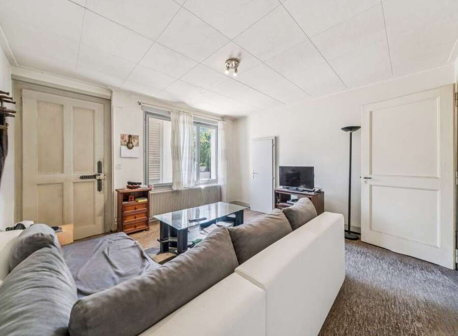 This living room features a comfortable white sectional sofa with grey cushions, perfect for relaxing.