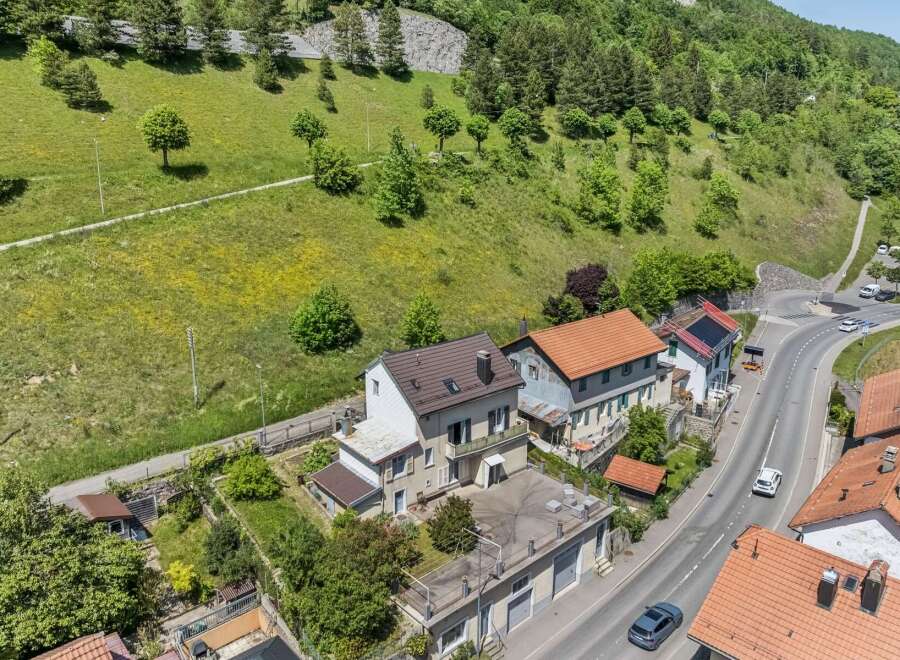 Discover this charming property nestled against a lush green hillside, offering a serene escape with stunning natural views.