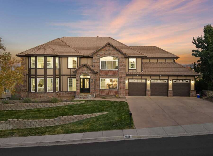 This stunning two-story home boasts a charming Tudor-inspired exterior with brick accents and a warm, inviting color palette.