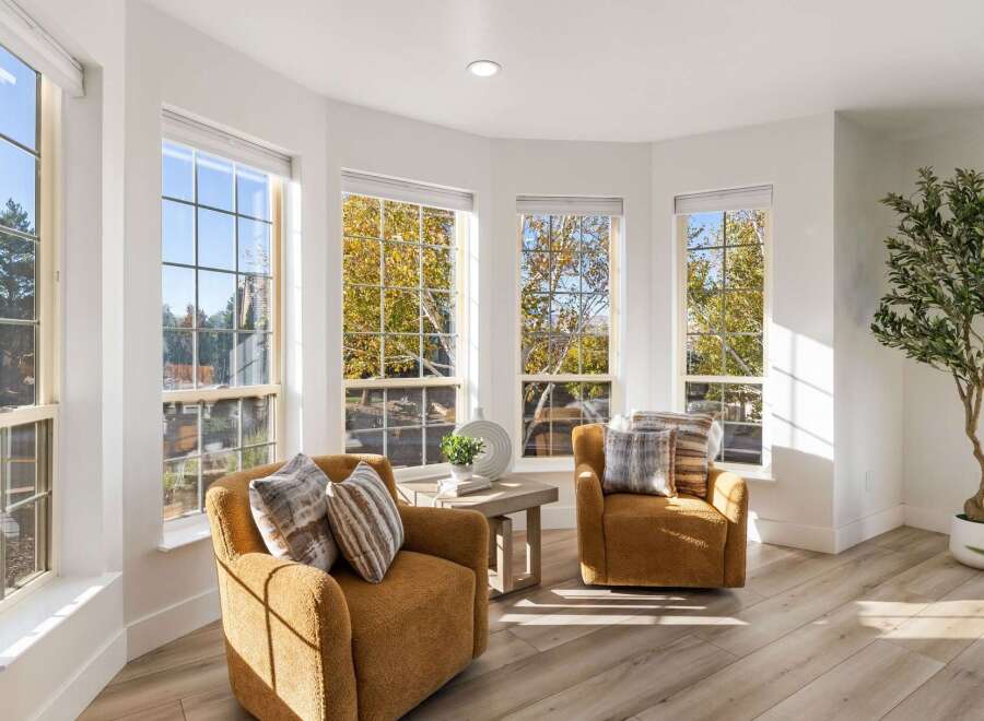 Bathed in natural light, this inviting living space features two plush, mustard-yellow armchairs perfect for relaxation.