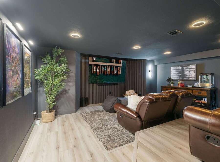 Experience cinematic bliss in this modern basement home theater, featuring plush leather recliners and a large screen perfect for movie nights.
