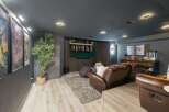Experience cinematic bliss in this modern basement home theater, featuring plush leather recliners and a large screen perfect for movie nights.