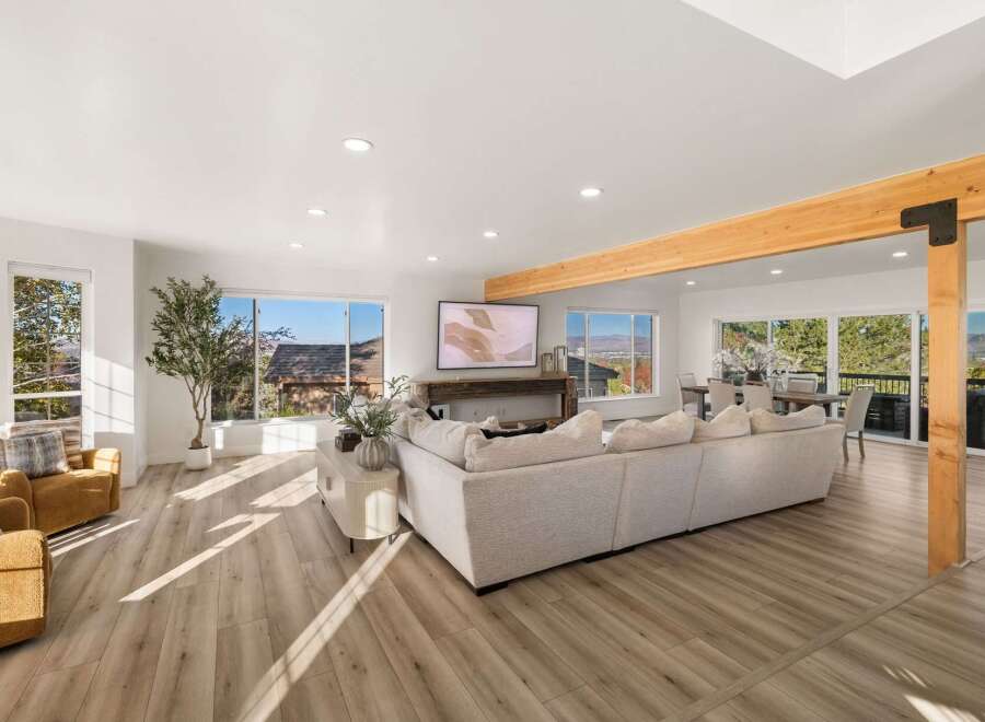 Experience breathtaking panoramic views from this stunning living room, featuring a spacious sectional sofa and two cozy accent chairs perfect for relaxation.