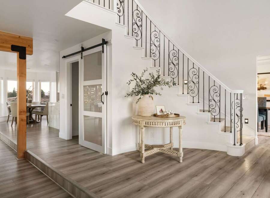 Step into a grand foyer featuring a stunning staircase with ornate black railings and a modern sliding glass door.