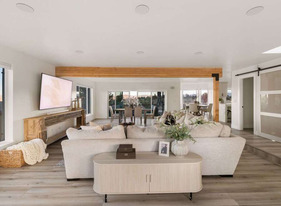 Experience modern living in this open-concept home, featuring a spacious living area with a large sectional sofa and a wall-mounted TV.