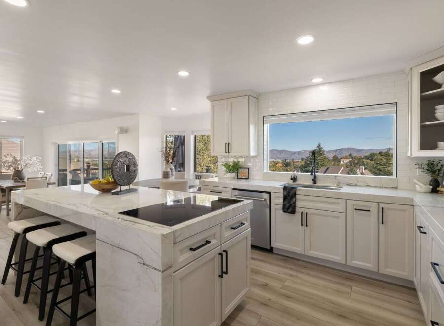 Experience breathtaking mountain views from this stunning modern kitchen, featuring a large island with a built-in stovetop and ample seating.